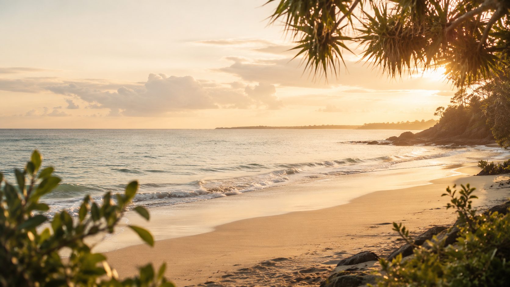 A calm shoreline at sunset with soft waves and coastal greenery