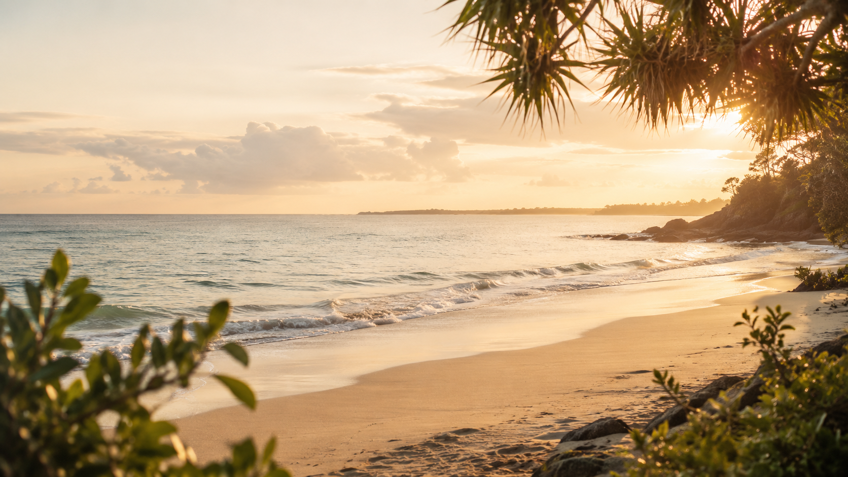 A calm shoreline at sunset with soft waves and coastal greenery